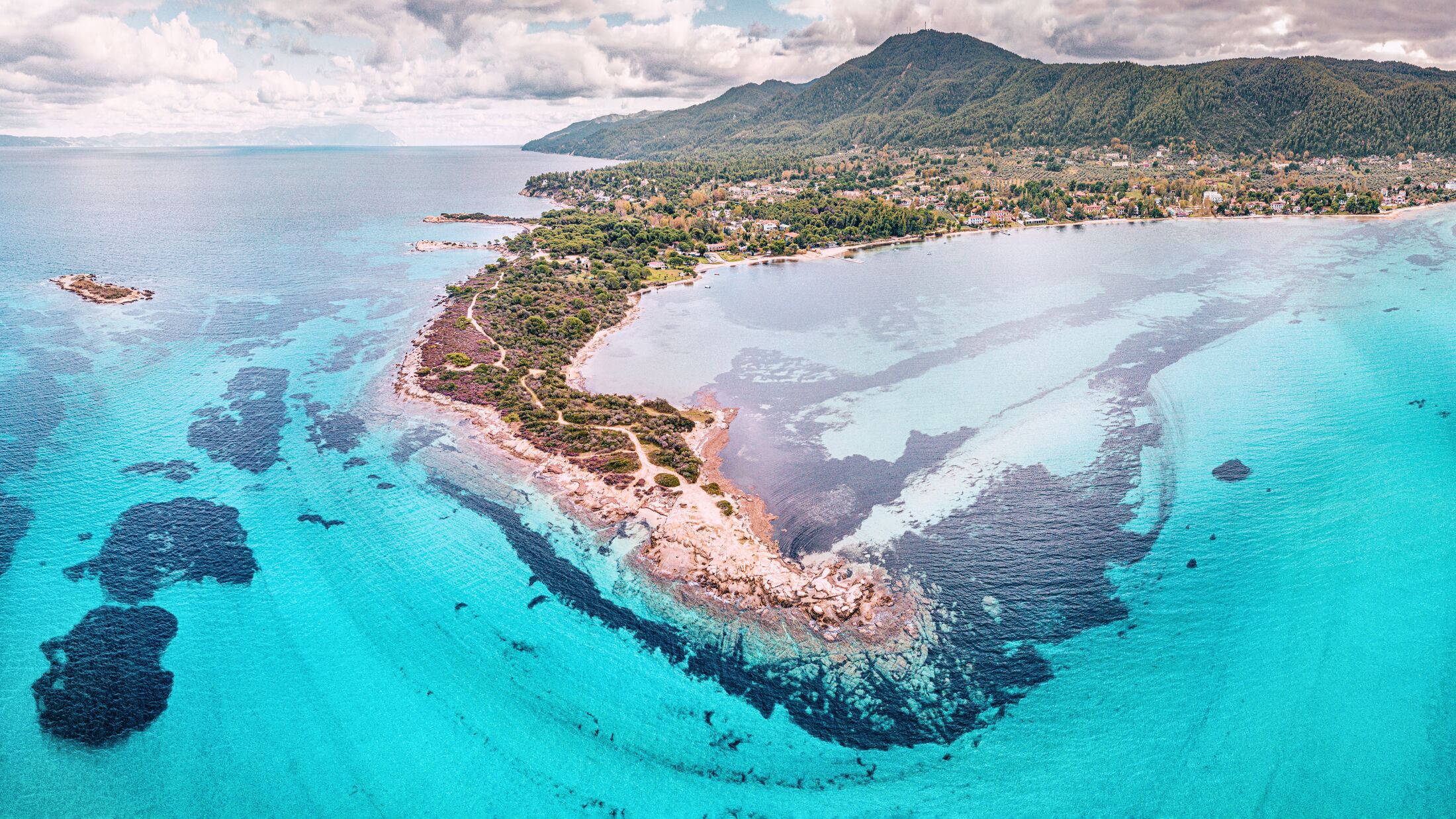 Amazing aerial view of the paradise seacoast with various shades of turquoise water. Idyllic sandy beaches and blue lagoons and bays in the resort village of Vourvourou in Halkidiki, Greece
